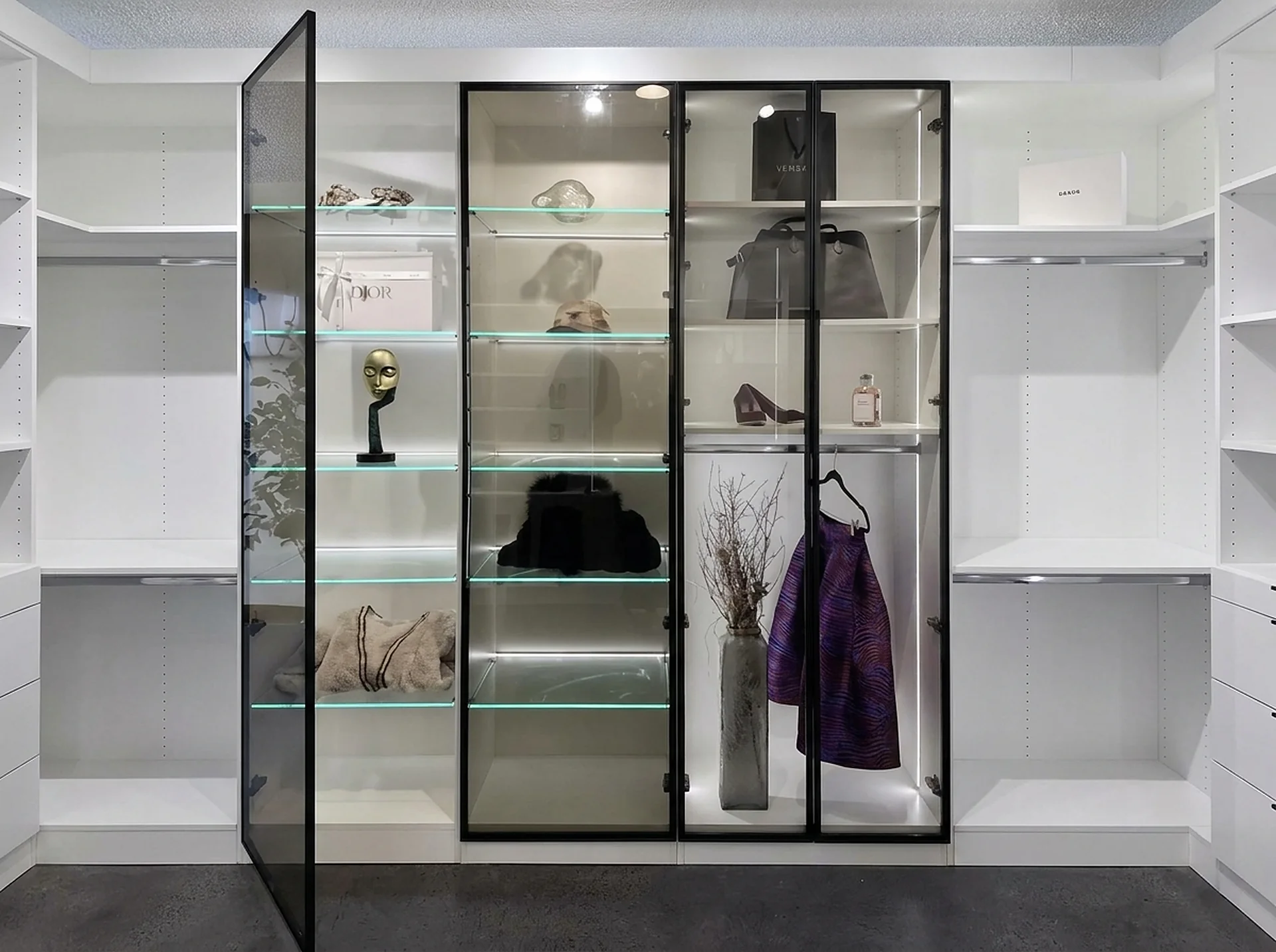 Closet with black framed glass doors and lit glass shelves
