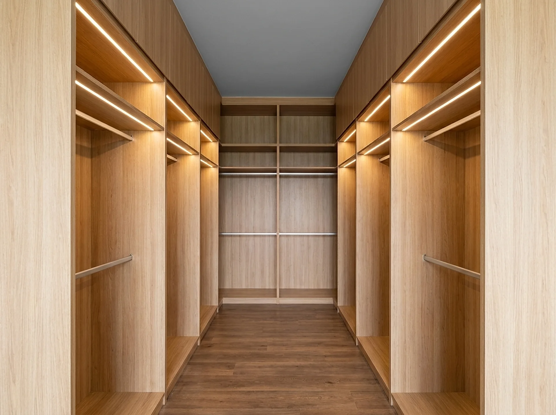 Warm reach-in custom closet with integrated LED shelf lighting