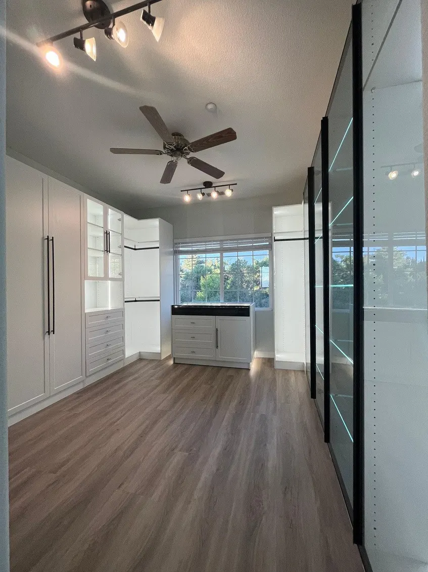 White closet suite with LED-lit glass display wall and black frame doors
